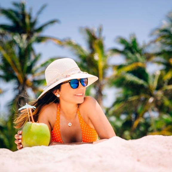 Woman on beach with coconut cocktail